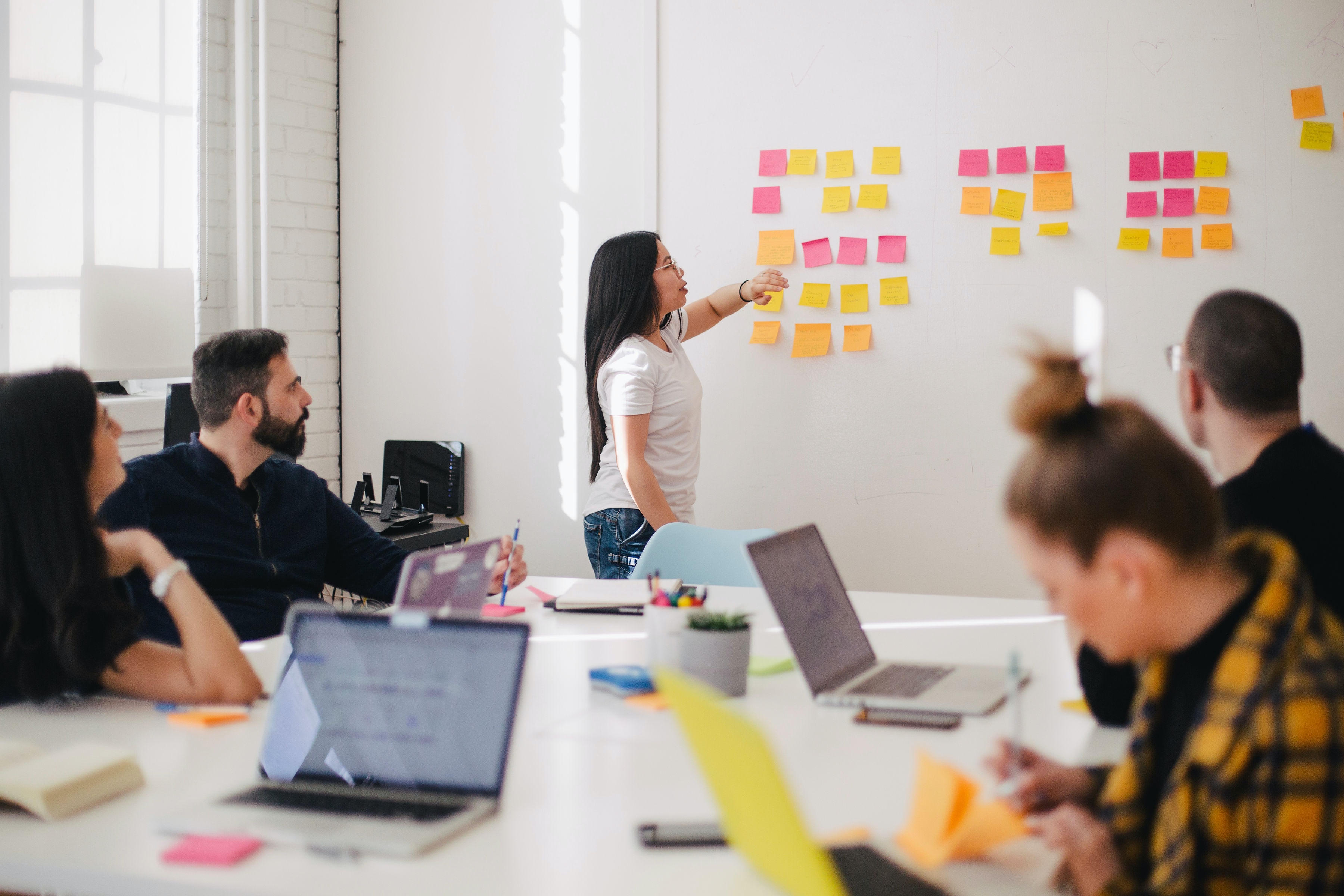 An individual stood in front of white board placing a sticky note